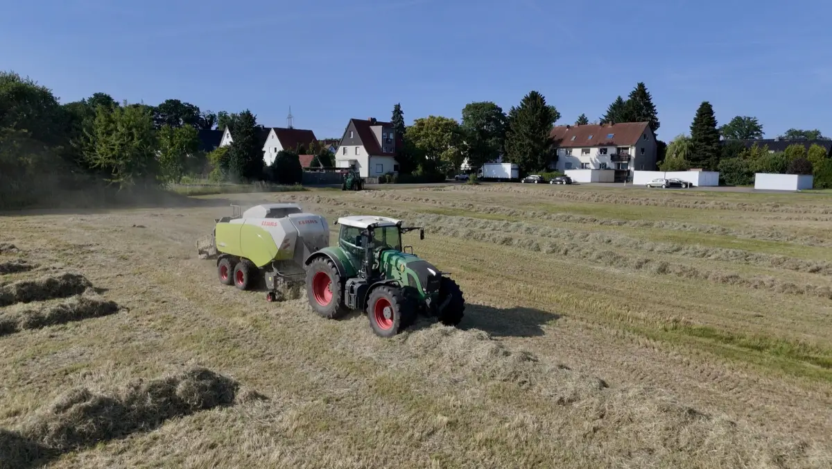 Traktor mit Ballenpresse beim Pressen von Strohballen